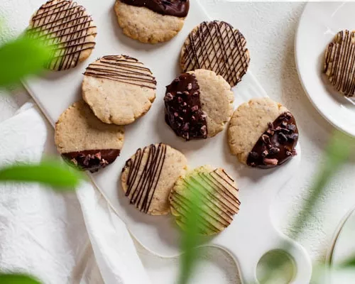 Vegan sugar cookies dipped and drizzled with chocolate on a cutting board